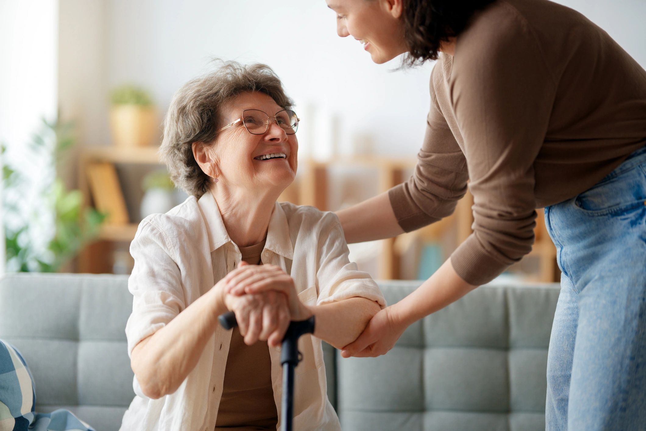 Happy senior woman with caregiver, smiling together in a home setting.